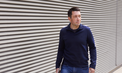 Dizüstü bilgisayarını elinde tutan Rob açık havada yürüyor.