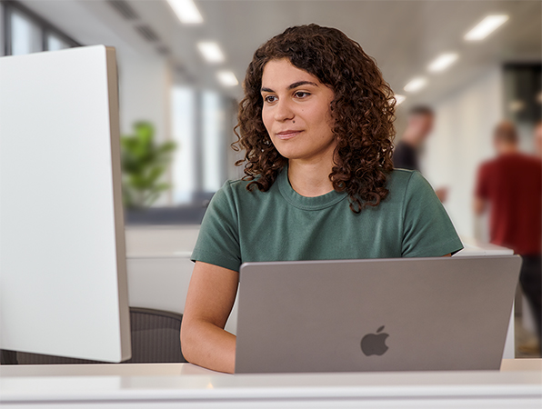 Ofiste MacBook ve Studio Display kullanan bir Apple ekip üyesi.