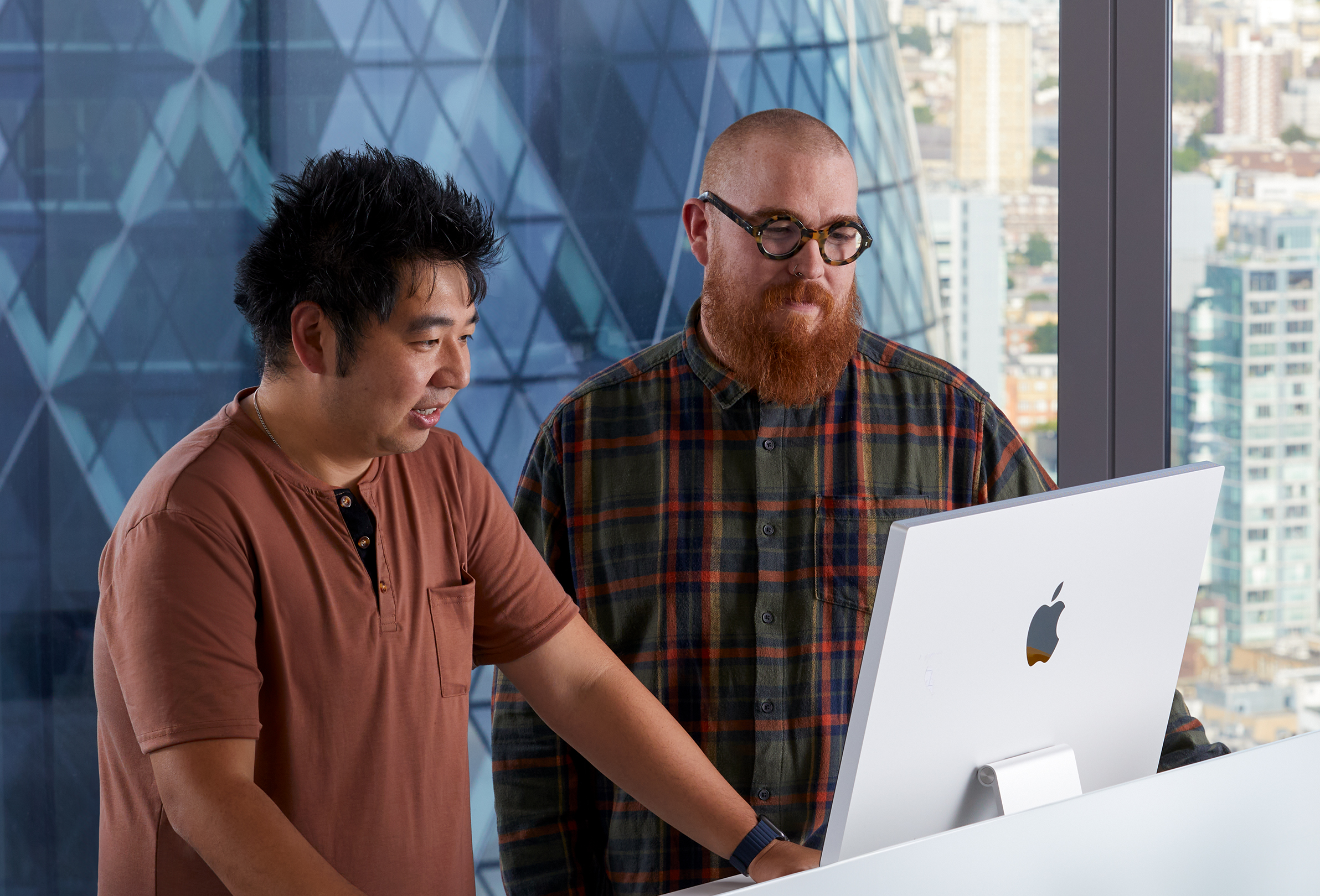 Bir iMac’i kullanarak birlikte çalışan iki Apple iş arkadaşı.