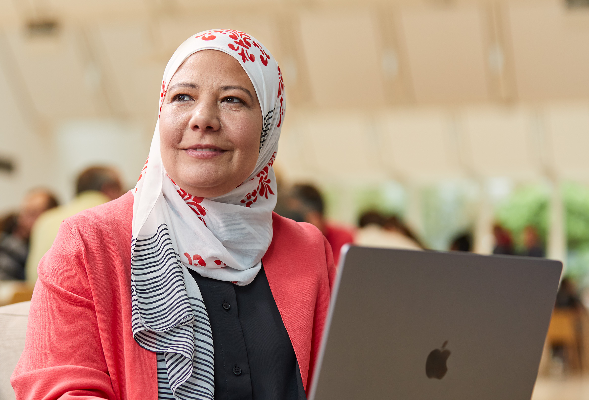 Oturan bir Apple çalışanı sola bakarak MacBook’ta çalışıyor.
