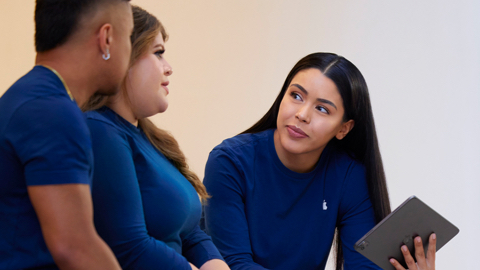 Biri elinde iPad tutan üç Apple Store ekip üyesi birlikte konuşuyor.