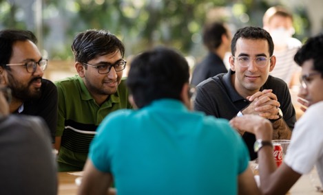 Um grupo de estagiários da Apple conversam em uma mesa no Caffè Macs.