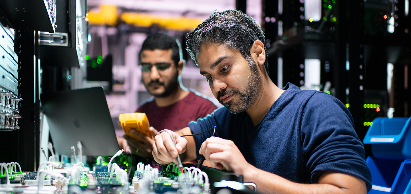 İki Apple mühendisi, laboratuvarda iPhone bileşenleri üzerinde çalışıyor.