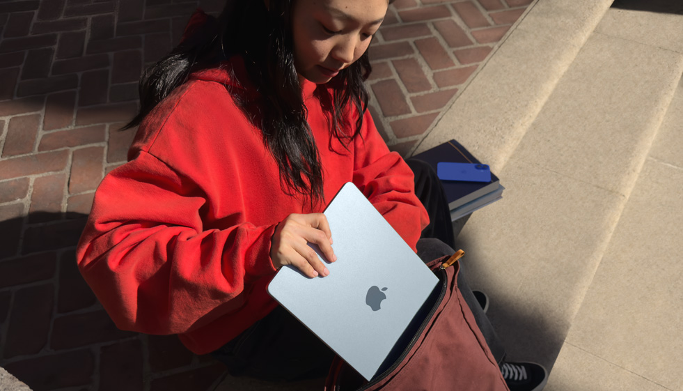 Eine Studentin legt ein MacBook Air in den Rucksack